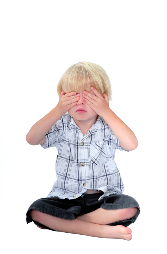Young boy with his hands over his eyes and white background